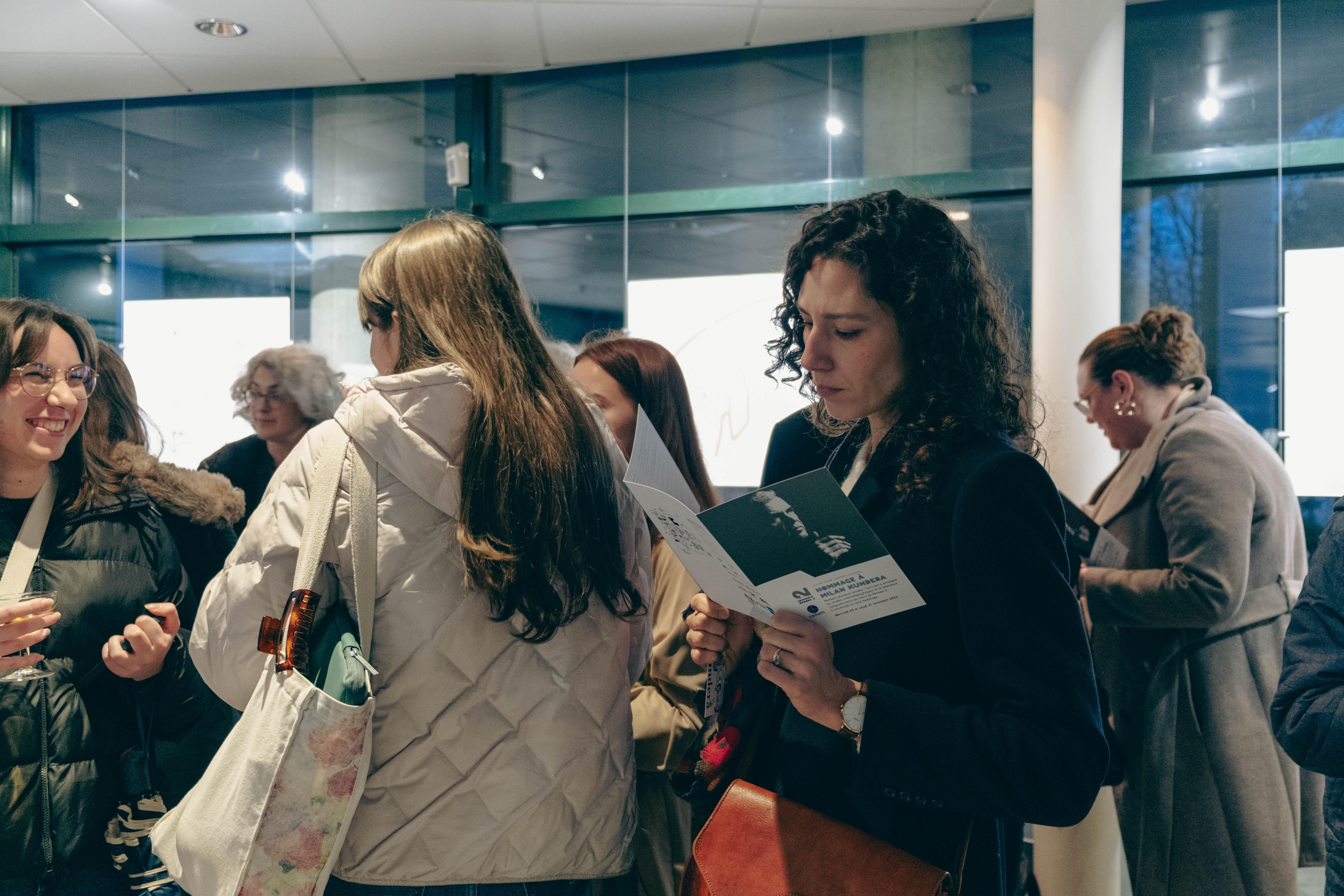 une femme lit le programme de l'hommage à Kundera à Rennes 2