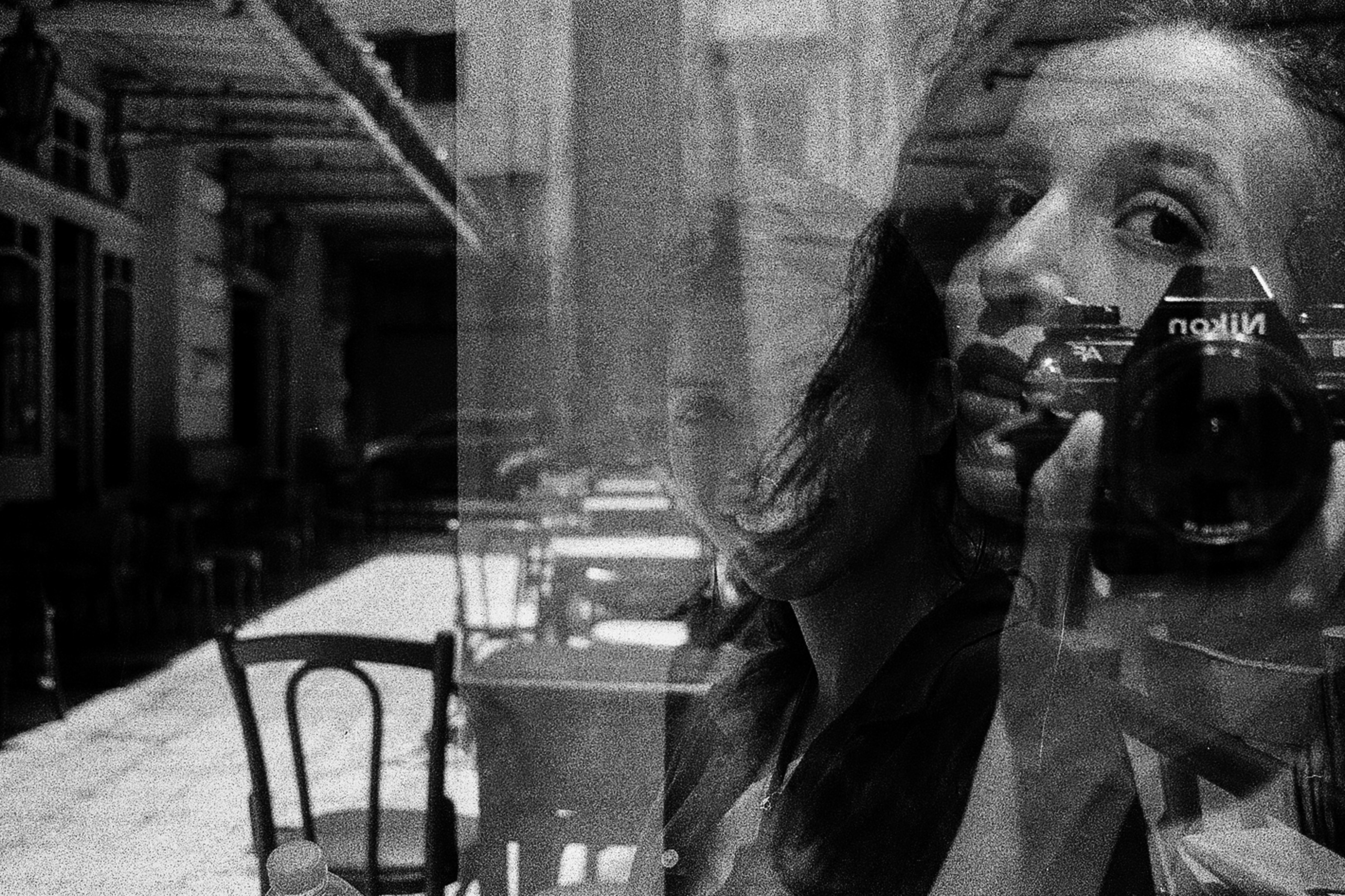 deux photos en noir et blanc superposées : l'une montre un visage proche en autoportrait, l'autre une table en terrasse au soleil