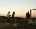 Trois personnes dans la rue, sur fond de nuit tombante