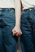 Photo en plan rapproché où on y voit deux femmes en jeans se tenir la main 