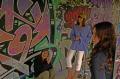 Photo de trois jeunes femmes souriantes devant des graffiti artistiques
