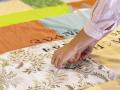photo d'une personne en train d'encrer des lettres sur une couverture en patchwork