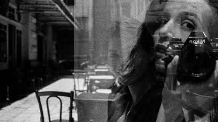 deux photos en noir et blanc superposées : l'une montre un visage proche en autoportrait, l'autre une table en terrasse au soleil