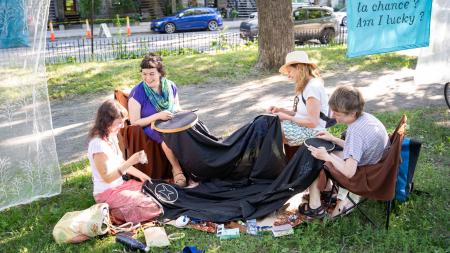 4 femmes brodent des étoiles sur un même tissu dans un parc