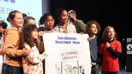 des enfants tiennent fièrement une affiche qu'ils et elles ont réalisée