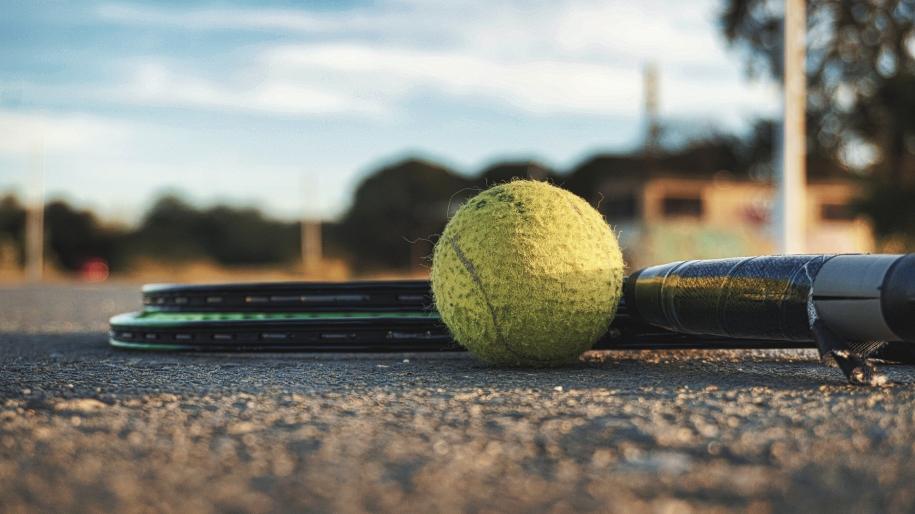 Photo d'une balle de tennis au sol à côté de 2 raquettes