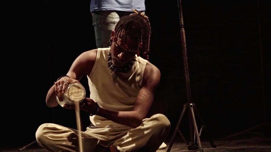 homme assis sur la scène versant quelque chose