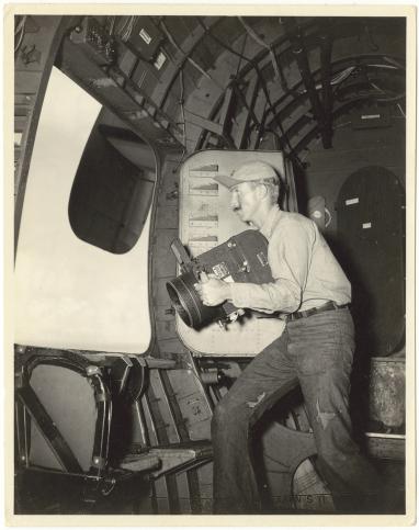 Photographie noir et blanc de 1946, montrant un photographe à bord d'un avion.