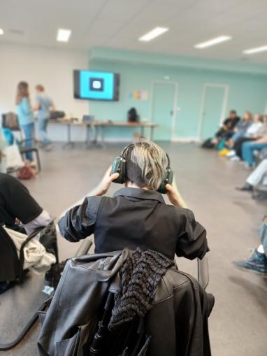 Personne de dos avec un casque sur la tête pendant l'atelier surdités à Rennes 2