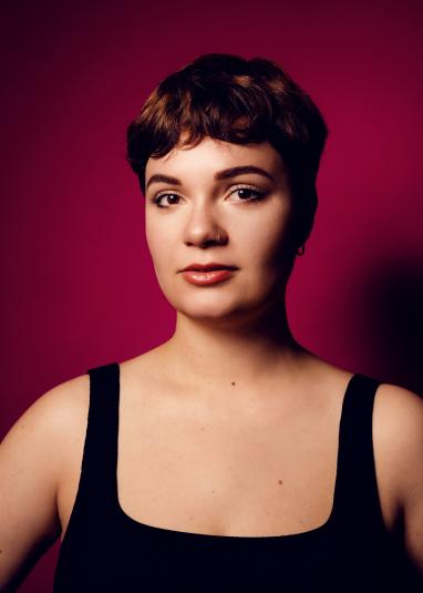 Portrait de Léane Alestra avec un fond rouge uni.