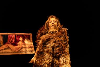 Photo de la comédienne Blanche Rérolle avec un manteau de fourrue et une moustache sur scène pour le spectacle Nos Poils.