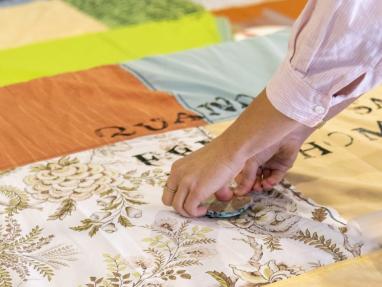 photo d'une personne en train d'encrer des lettres sur une couverture en patchwork