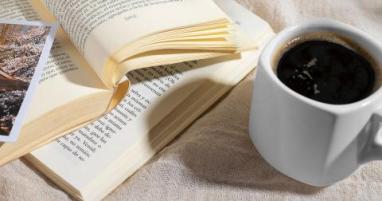 Une tasse de café à côté de deux livres ouverts