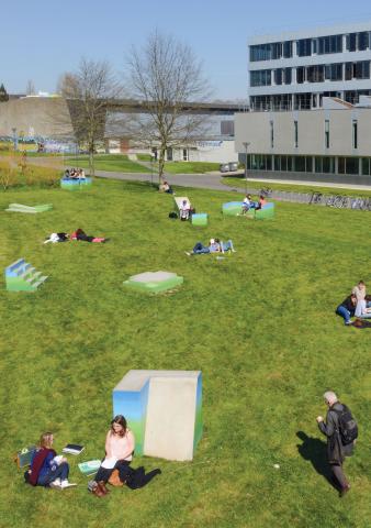 Des blocs de béton aux formes géométriques, peints entre ciel et terre, parsèment une pelouse.