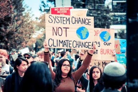 Photo de militants écologiques brandissant une pancarte "System change, not climate change"