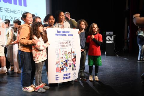 des enfants tiennent fièrement une affiche qu'ils et elles ont réalisée