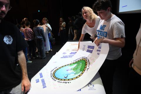 des enfants tiennent fièrement une affiche qu'ils et elles ont réalisée