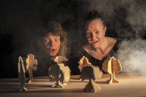 Deux femmes regardent des figurines en carton placés devant elles.